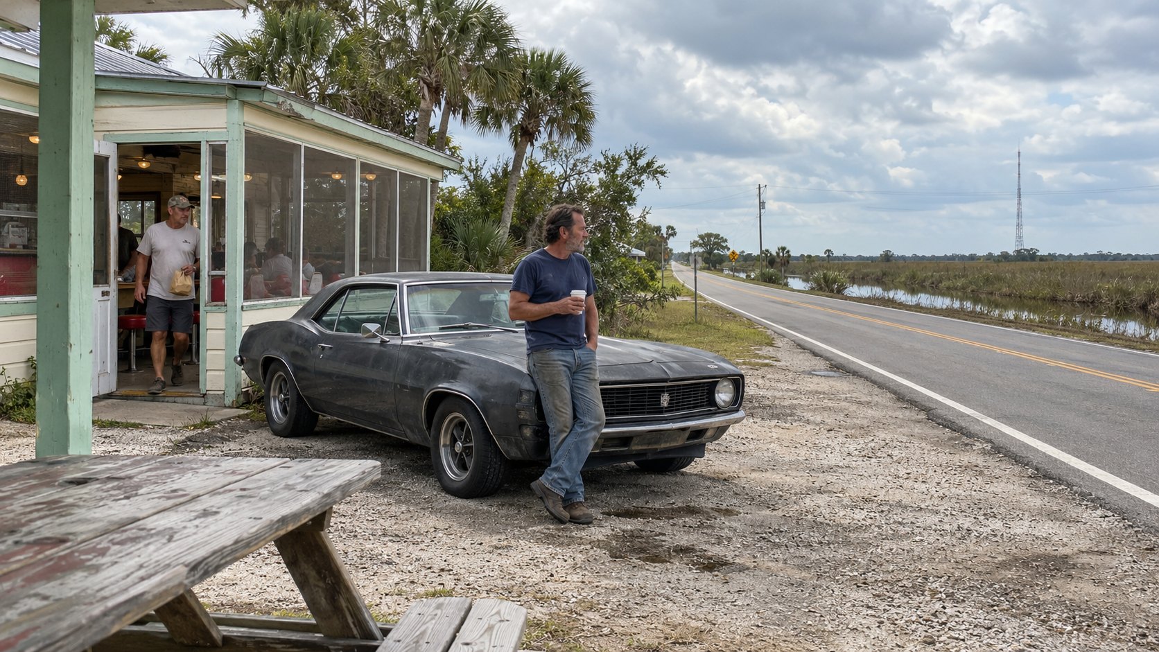 Roadside café and classic car beside an open wetland landscape